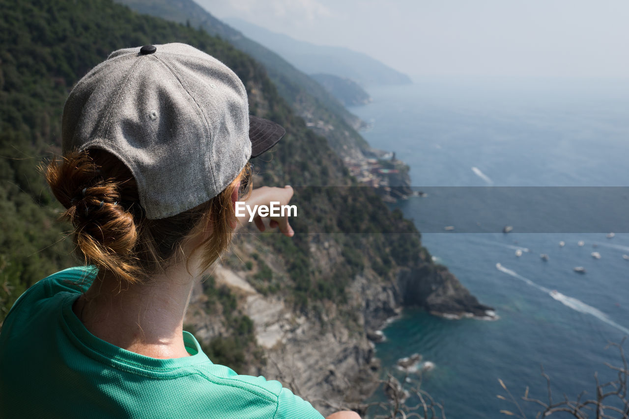 Rear view of young woman looking at sea while standing on mountain