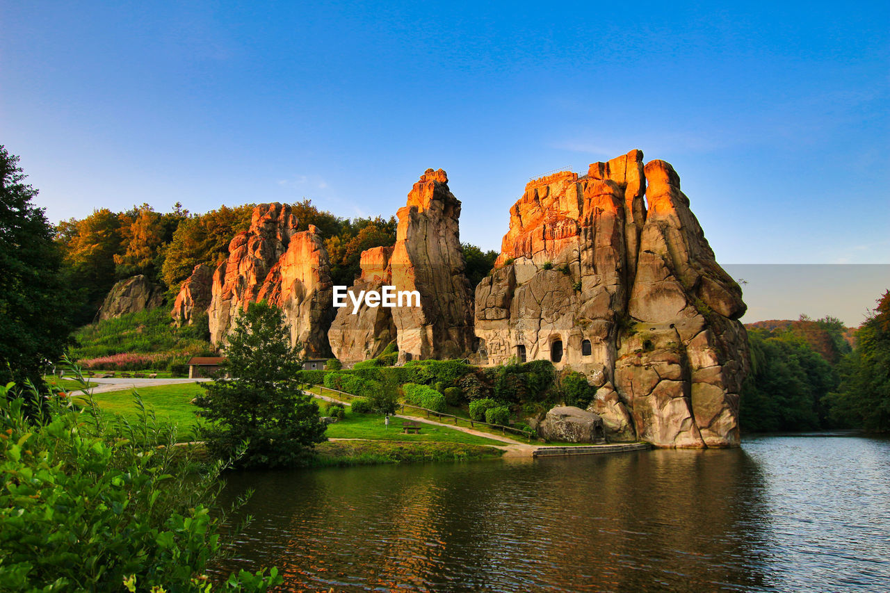 ROCK FORMATION BY RIVER AGAINST CLEAR SKY