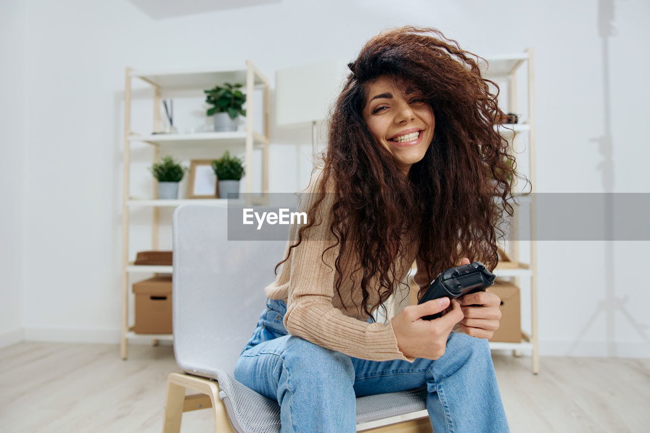 portrait of young woman using mobile phone while sitting at home