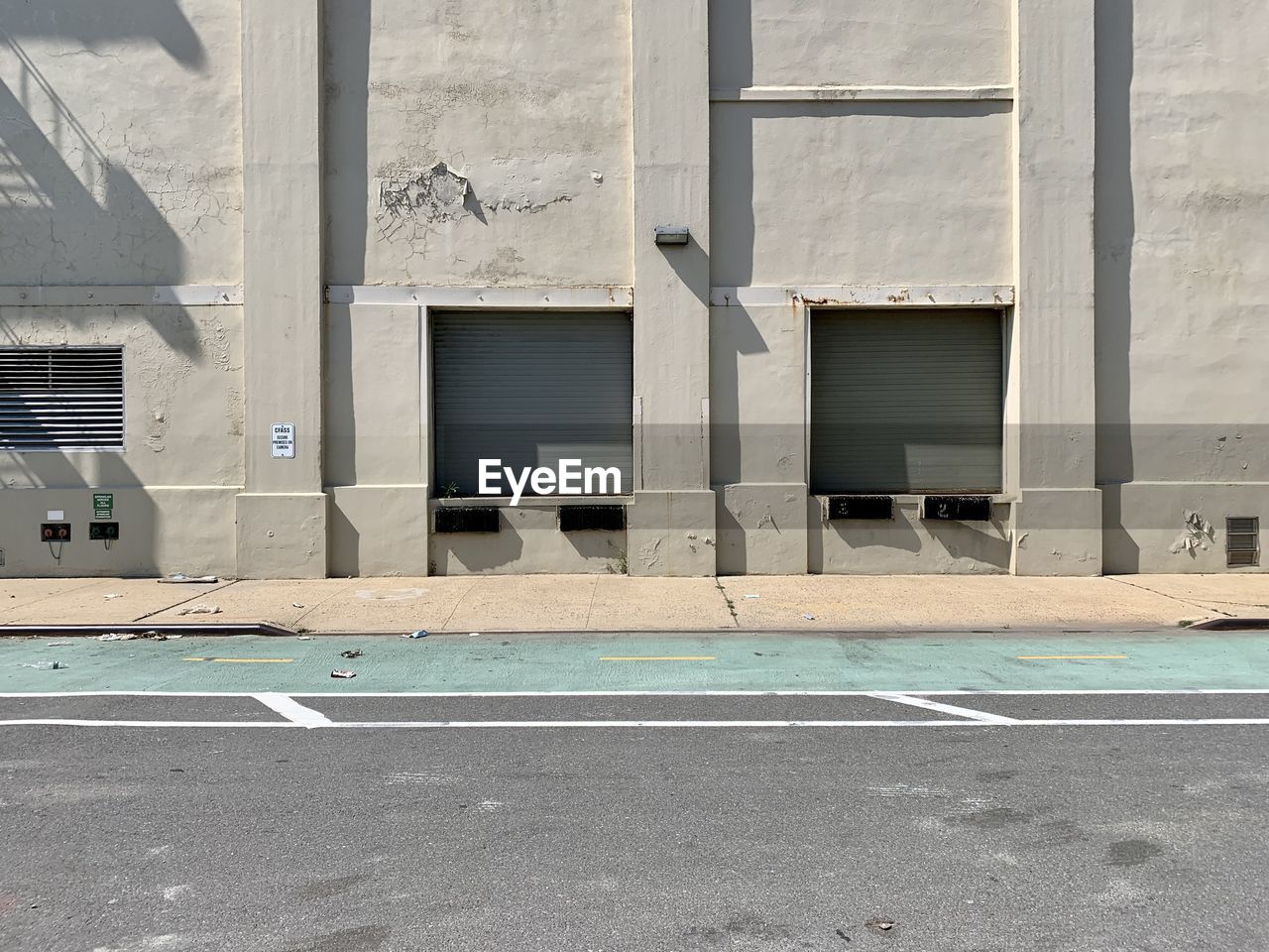 Empty road by storage building in city with closed loading docks