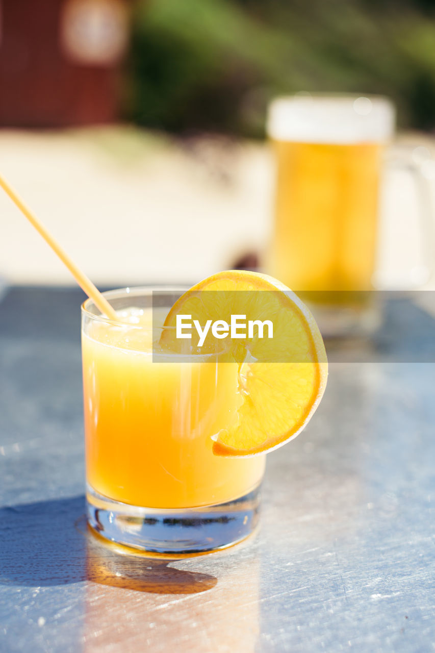 Drink glass with citrus fruit on table during sunny day