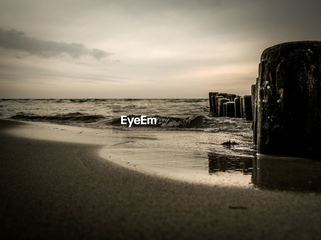 Scenic view of beach against cloudy sky