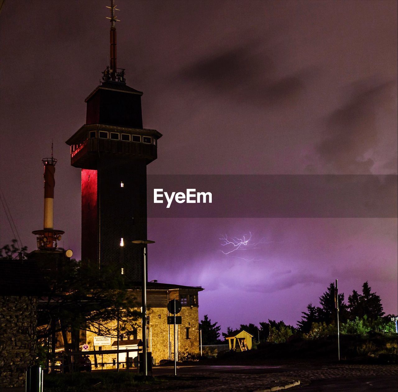 Street by building against cloudy sky with thunderstorm at night