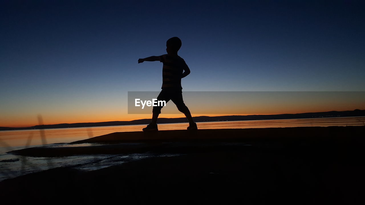 Kid punching air at dusk