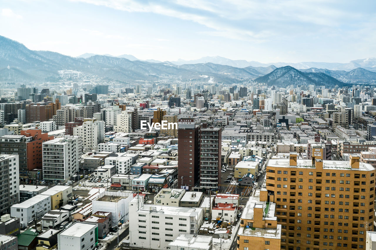 High angle view of urban skyline against cloudy sky