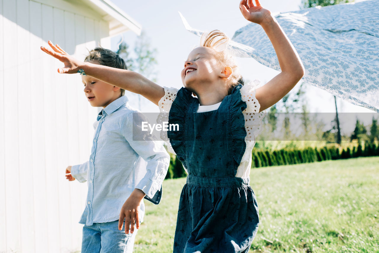 Girl and boy running through the washing on the line with great joy