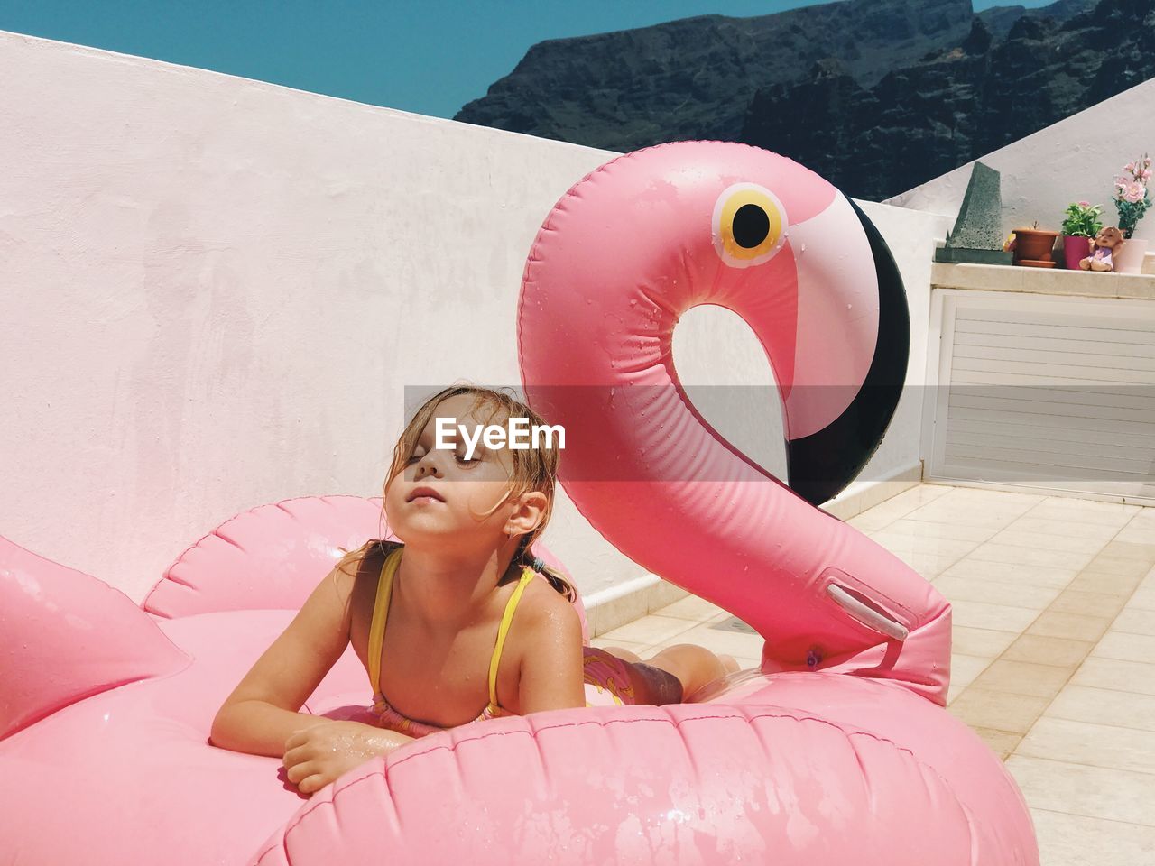 Girl relaxing on inflatable ring in swan shape during sunny day