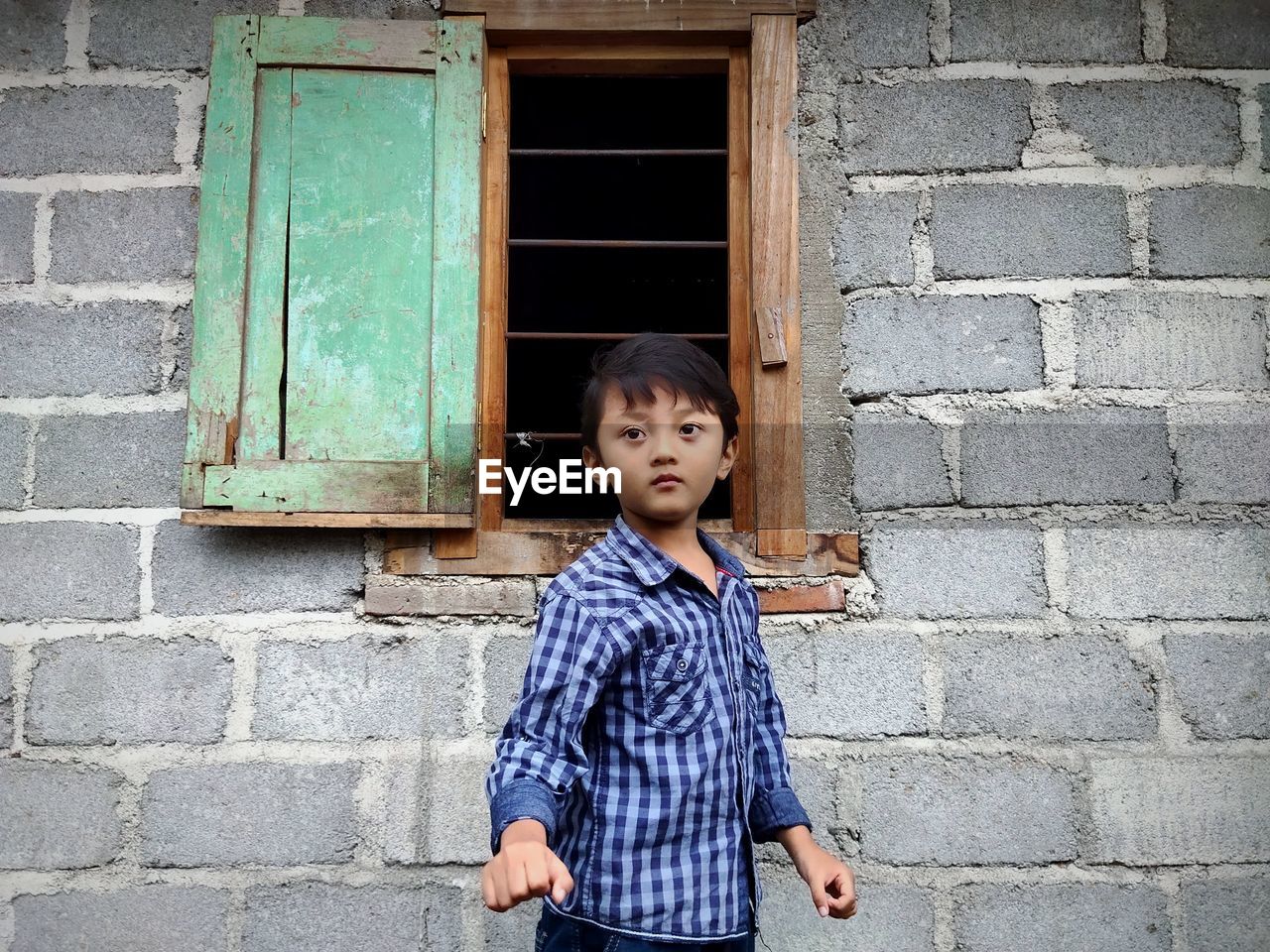 blue, one person, childhood, child, architecture, standing, portrait, men, casual clothing, building exterior, built structure, wall - building feature, looking at camera, window, person, building, lifestyles, shirt, front view, cute, emotion, clothing, looking, wall, innocence, day, outdoors, waist up, toddler, smiling, door, leisure activity, snapshot, female