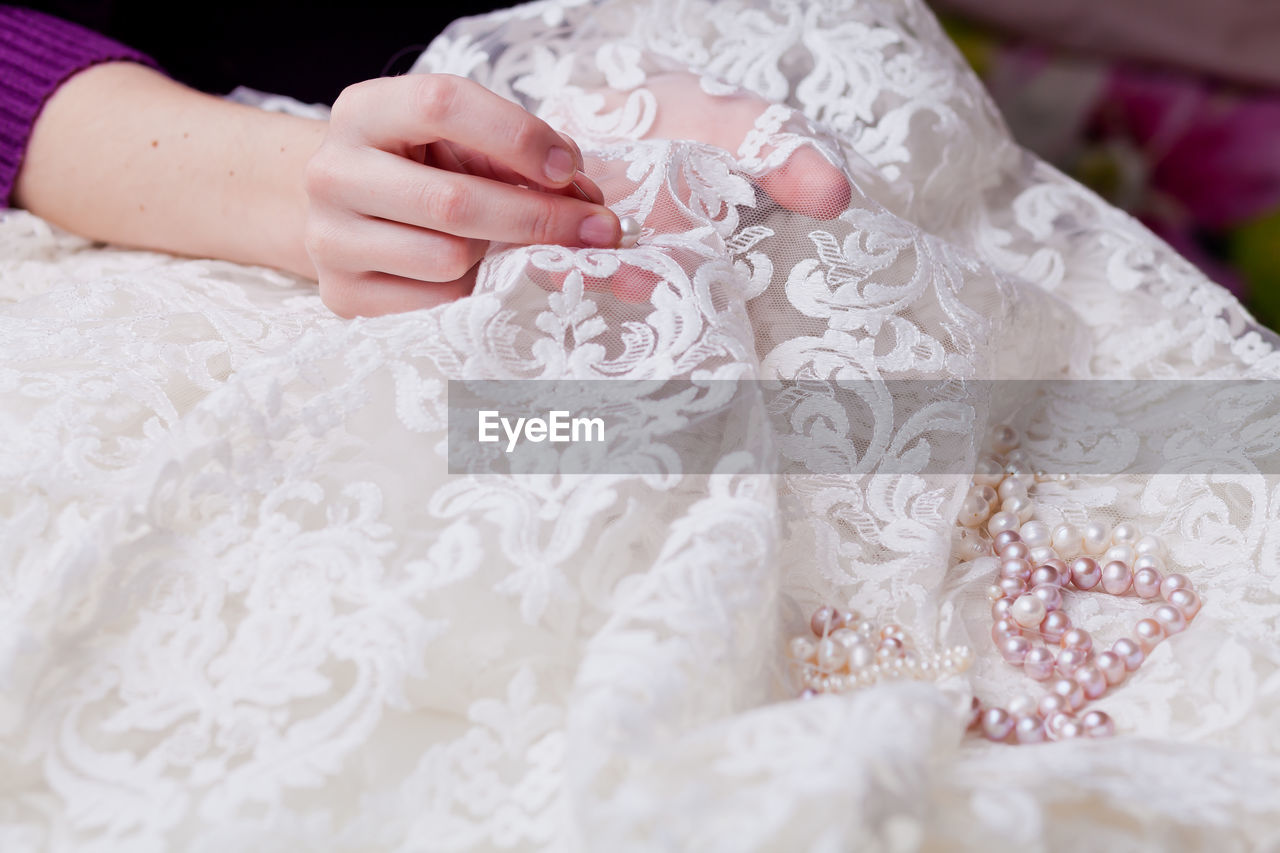 Cropped hands of woman stitching wedding dress