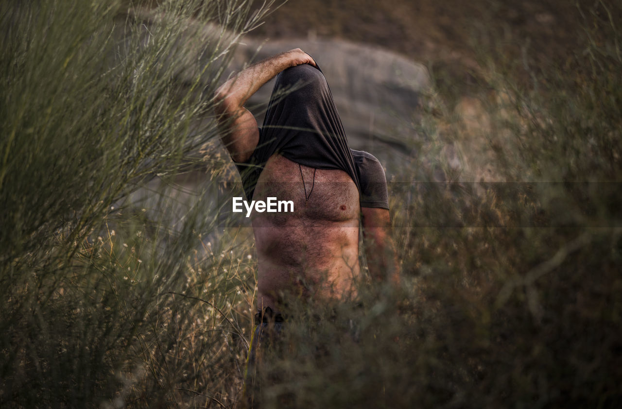 Man covering head with shirt in wood