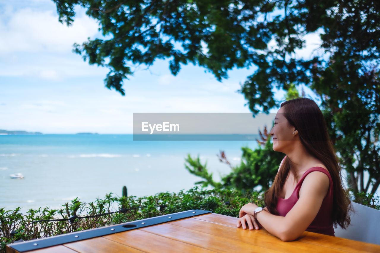 Side view of woman looking at sea against sky