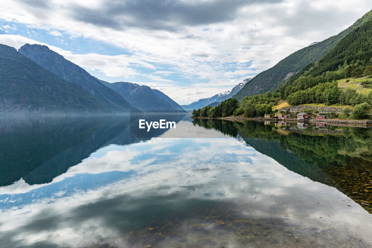 Scenic view of mountains reflecting on calm lake against cloudy sky