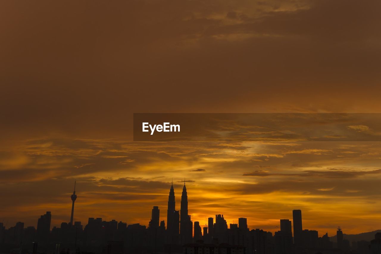 Silhouette of cityscape against orange sky during sunset