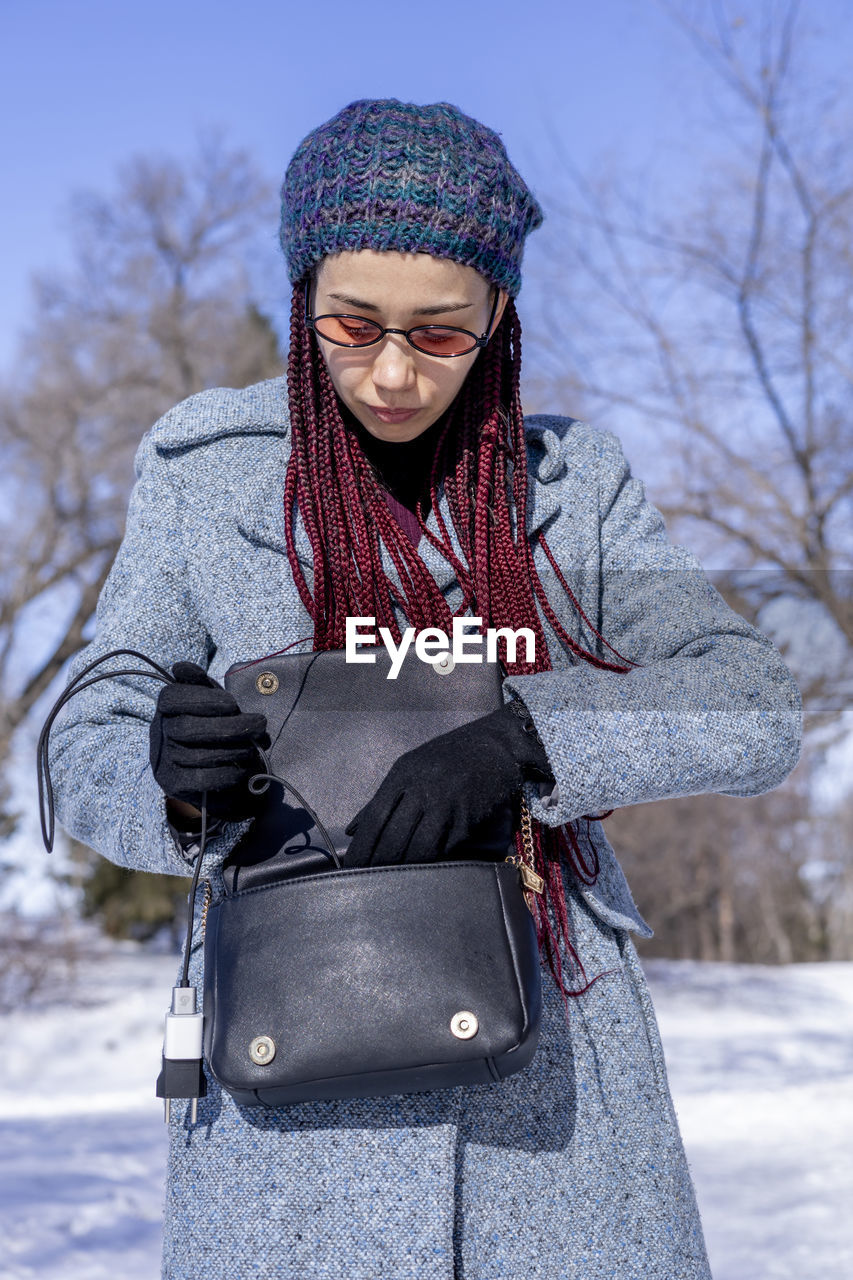 portrait of young woman wearing warm clothing standing against sky during winter