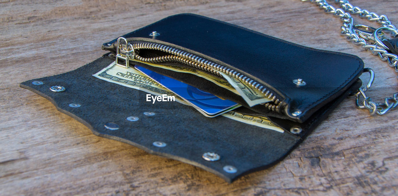 Close-up of paper currency with credit card in purse on table