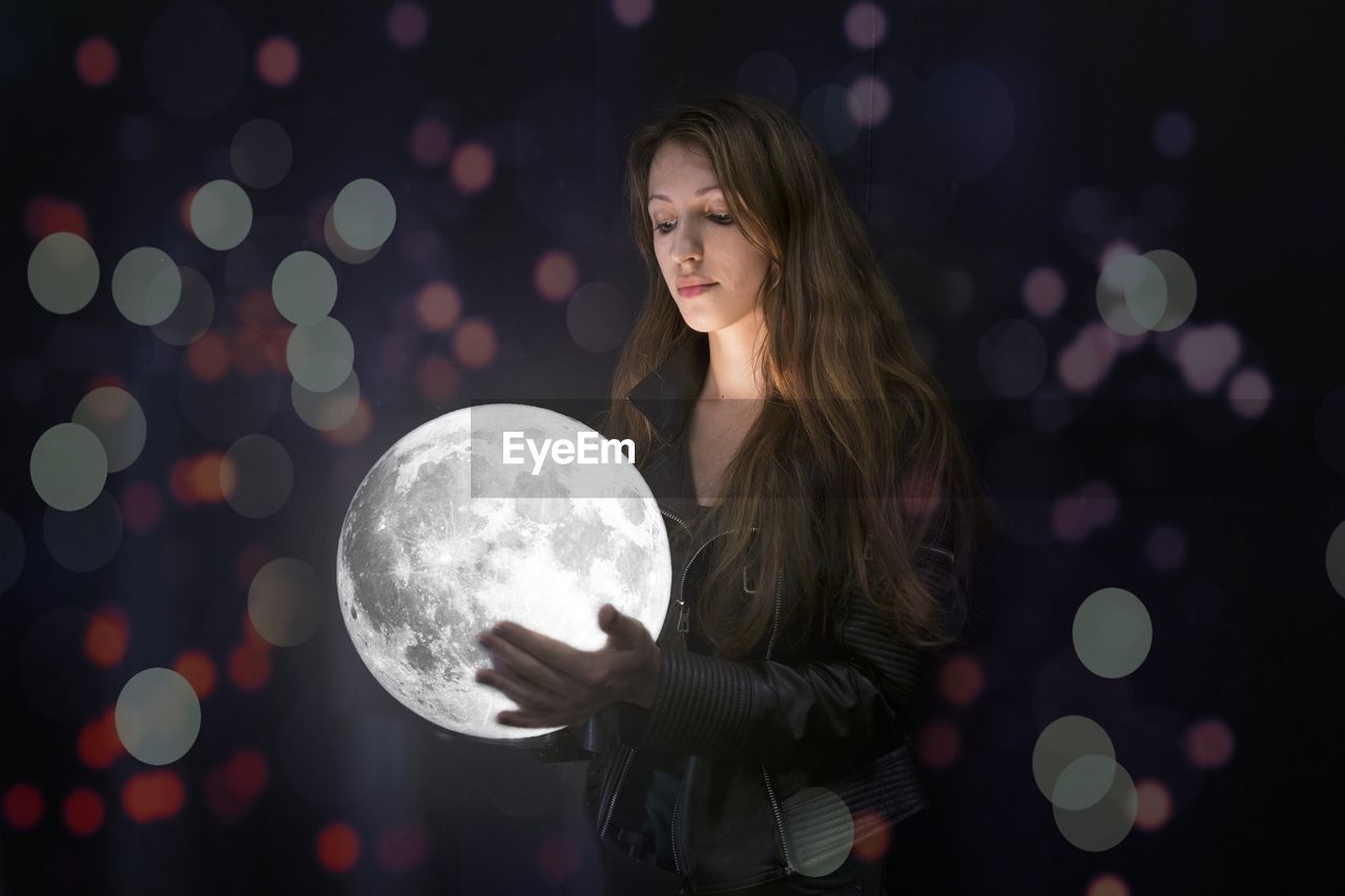 Digital composite image of young woman holding full moon