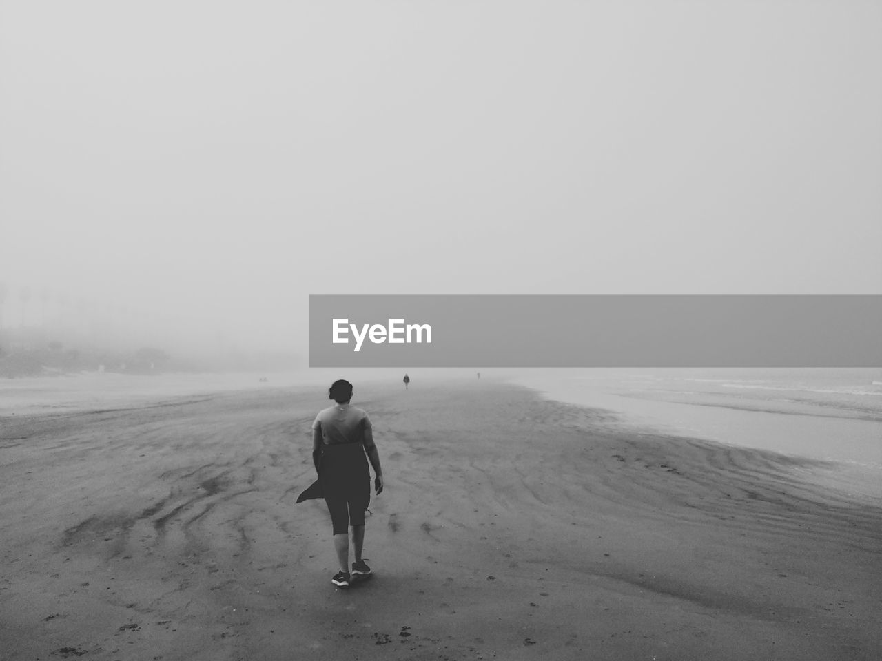 Rear view full length of man walking at beach during foggy weather