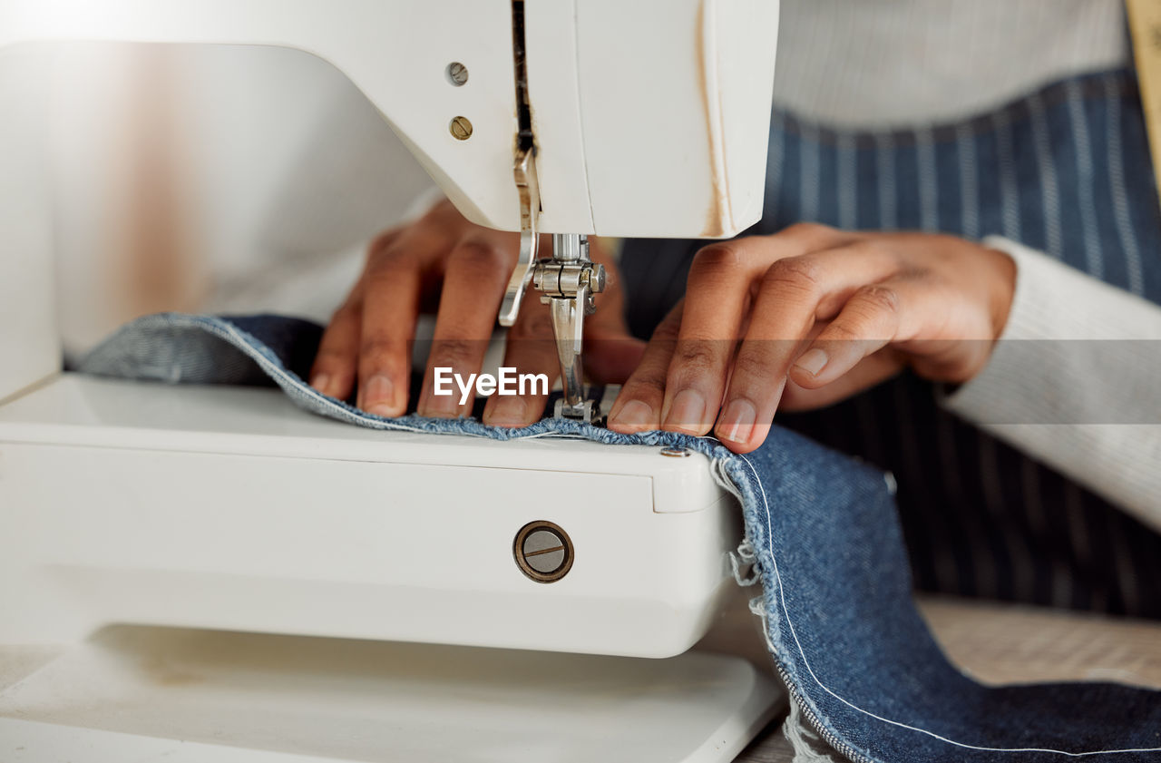 midsection of man using sewing machine