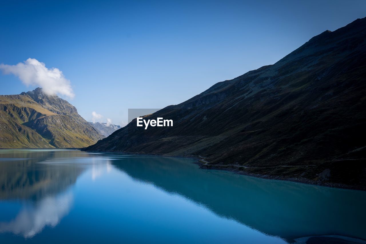 Scenic view of lake and mountains against blue sky