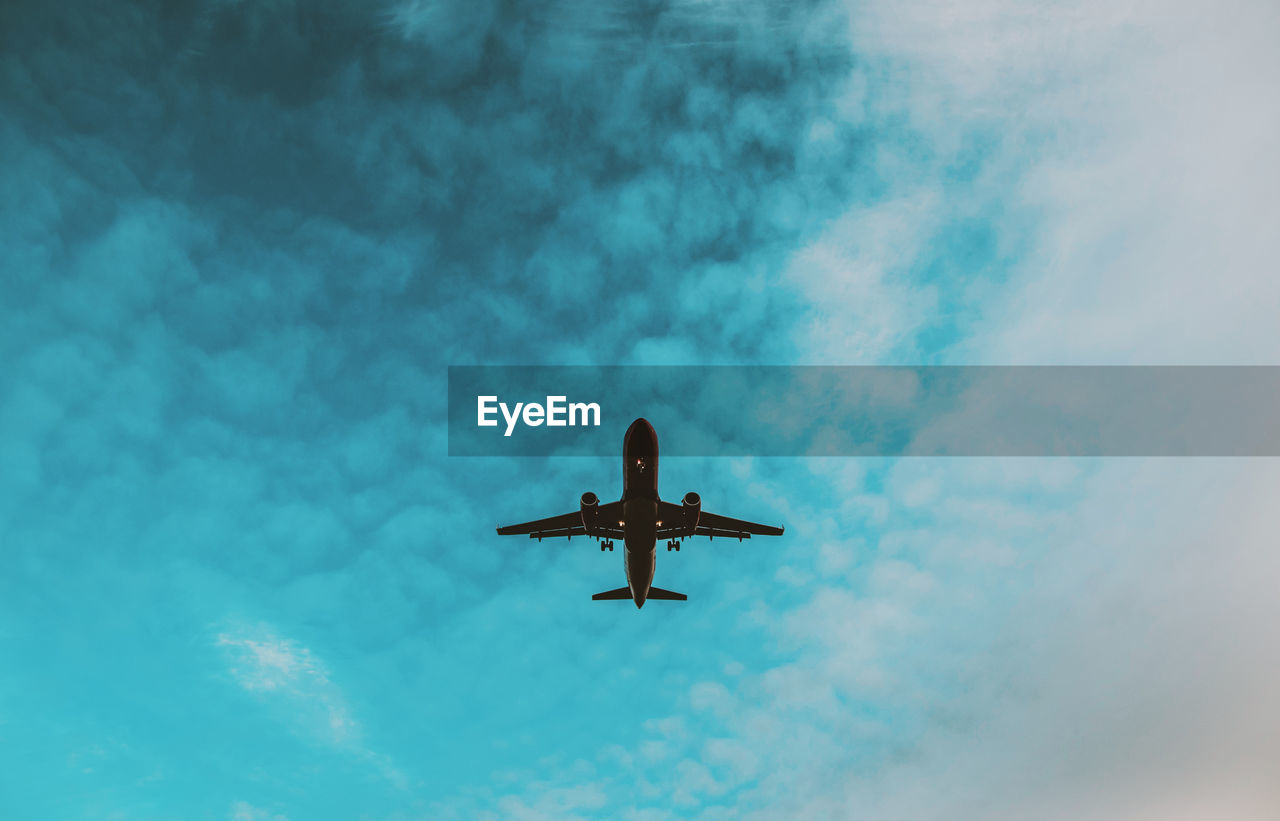 Low angle view of airplane against cloudy sky