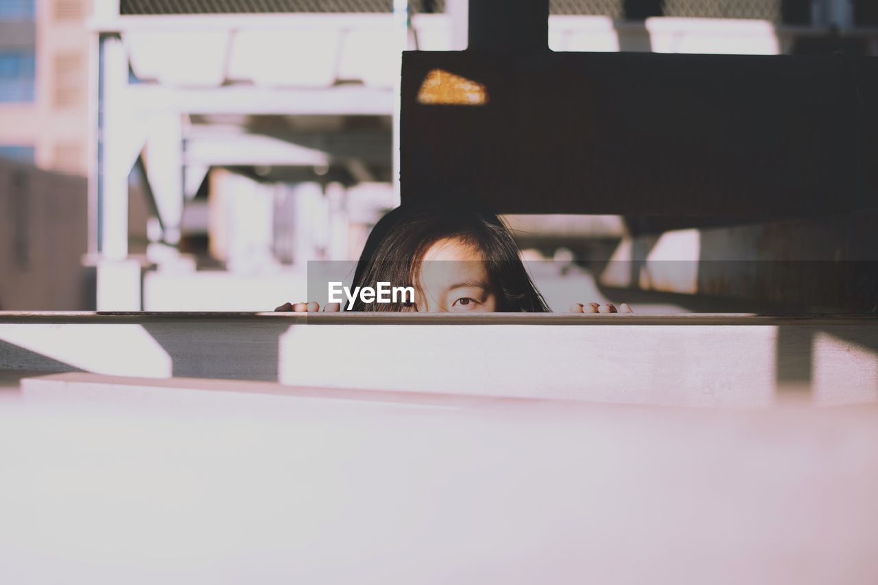 Portrait of woman peeking behind furniture