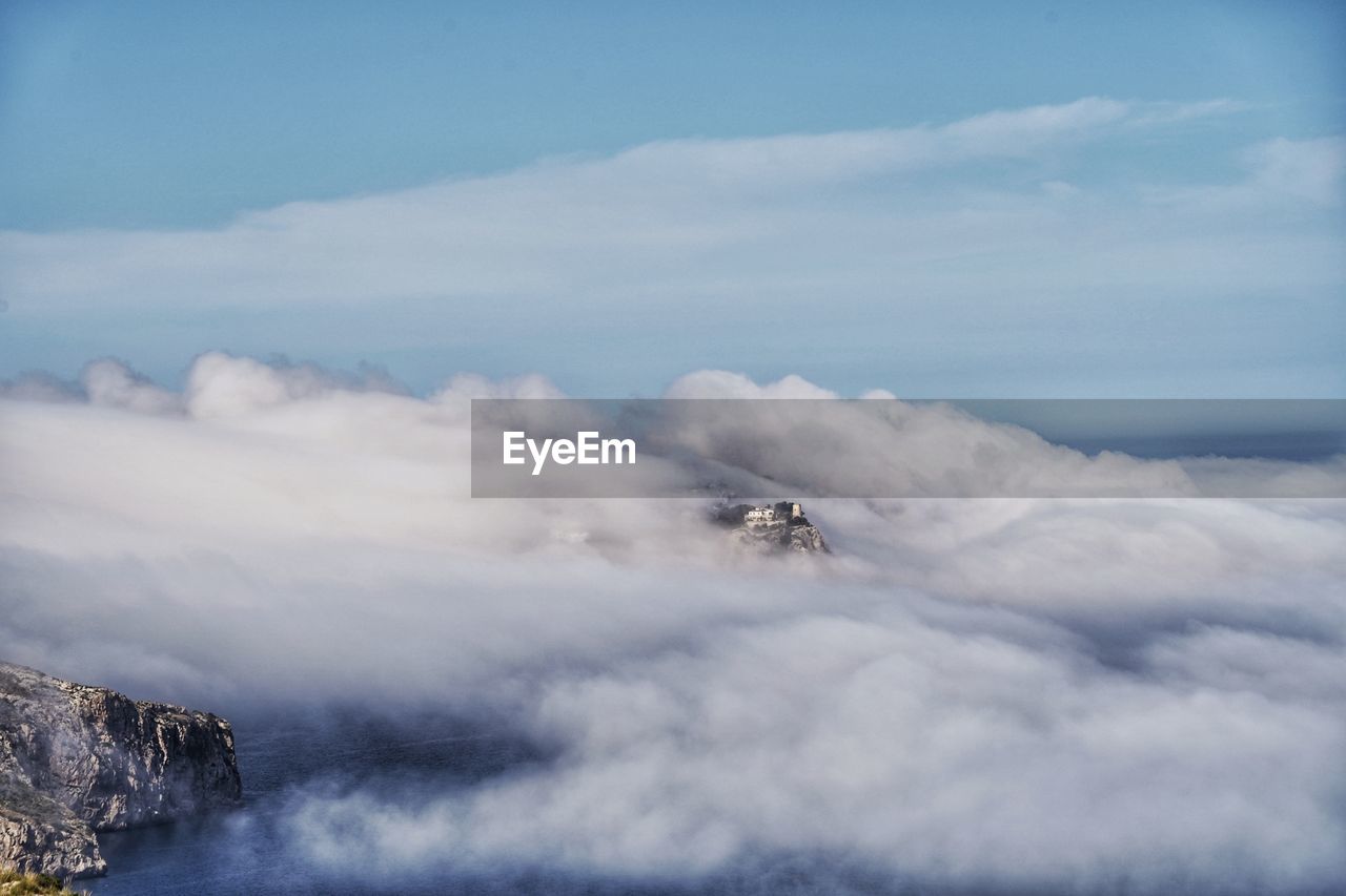 AIRPLANE FLYING OVER MOUNTAIN AGAINST SKY