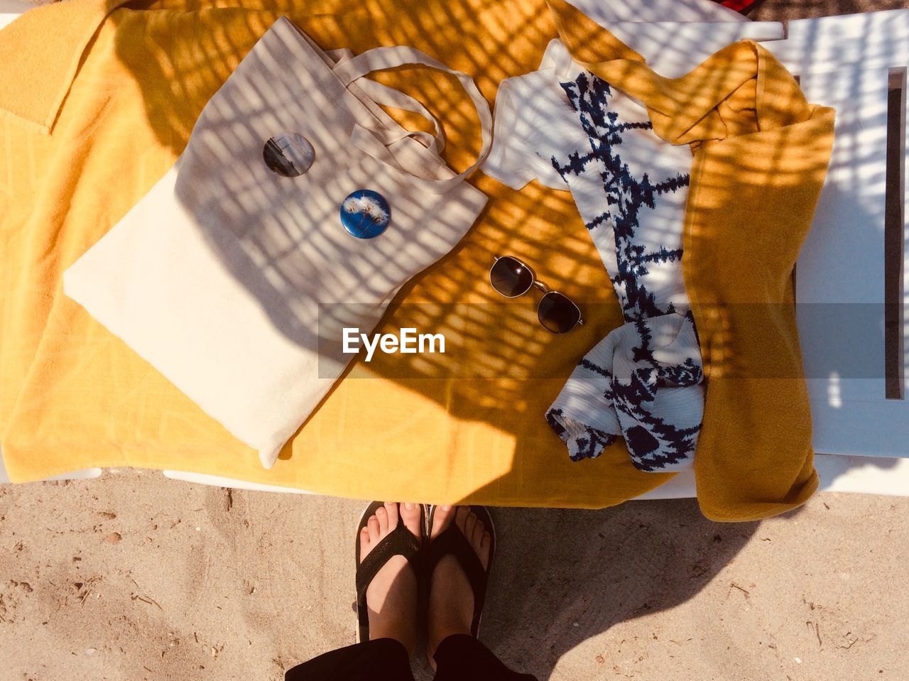 Low section of woman standing by beach blanket on sunny day