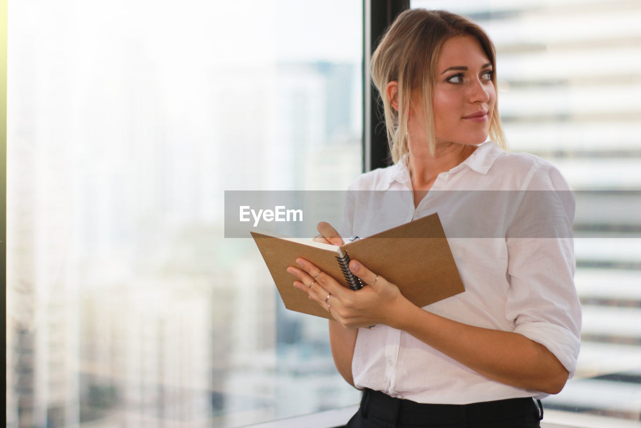 Portrait of a businesswoman holding notebook in modern office