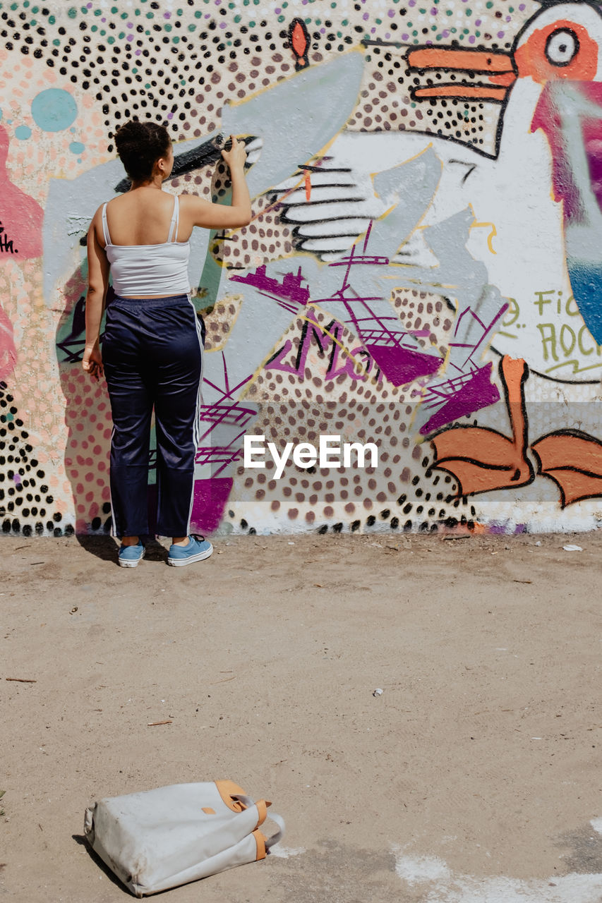 FULL LENGTH REAR VIEW OF WOMAN LOOKING AT CAMERA