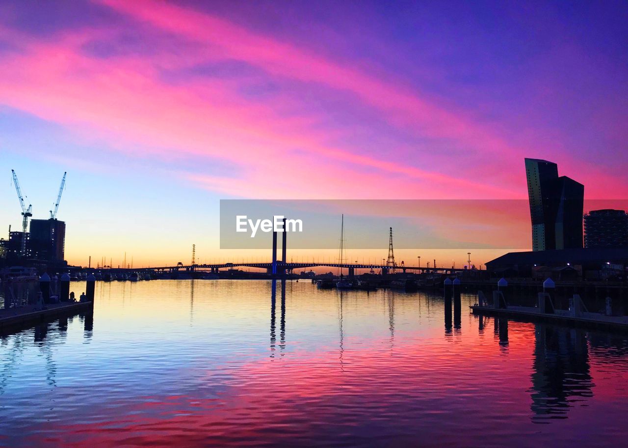 Scenic view of river amidst buildings against sky during sunset