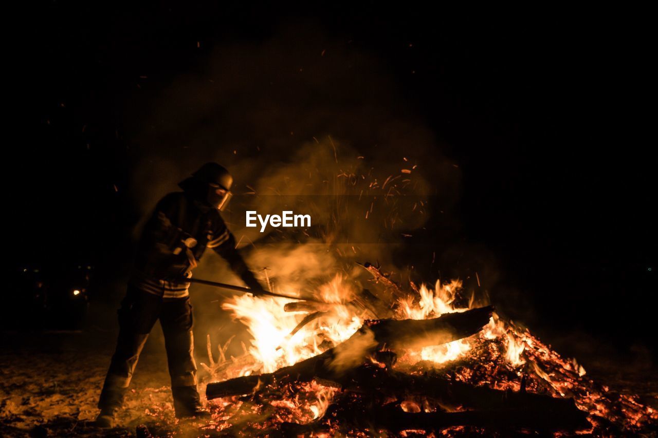 Firefighter against bonfire at night