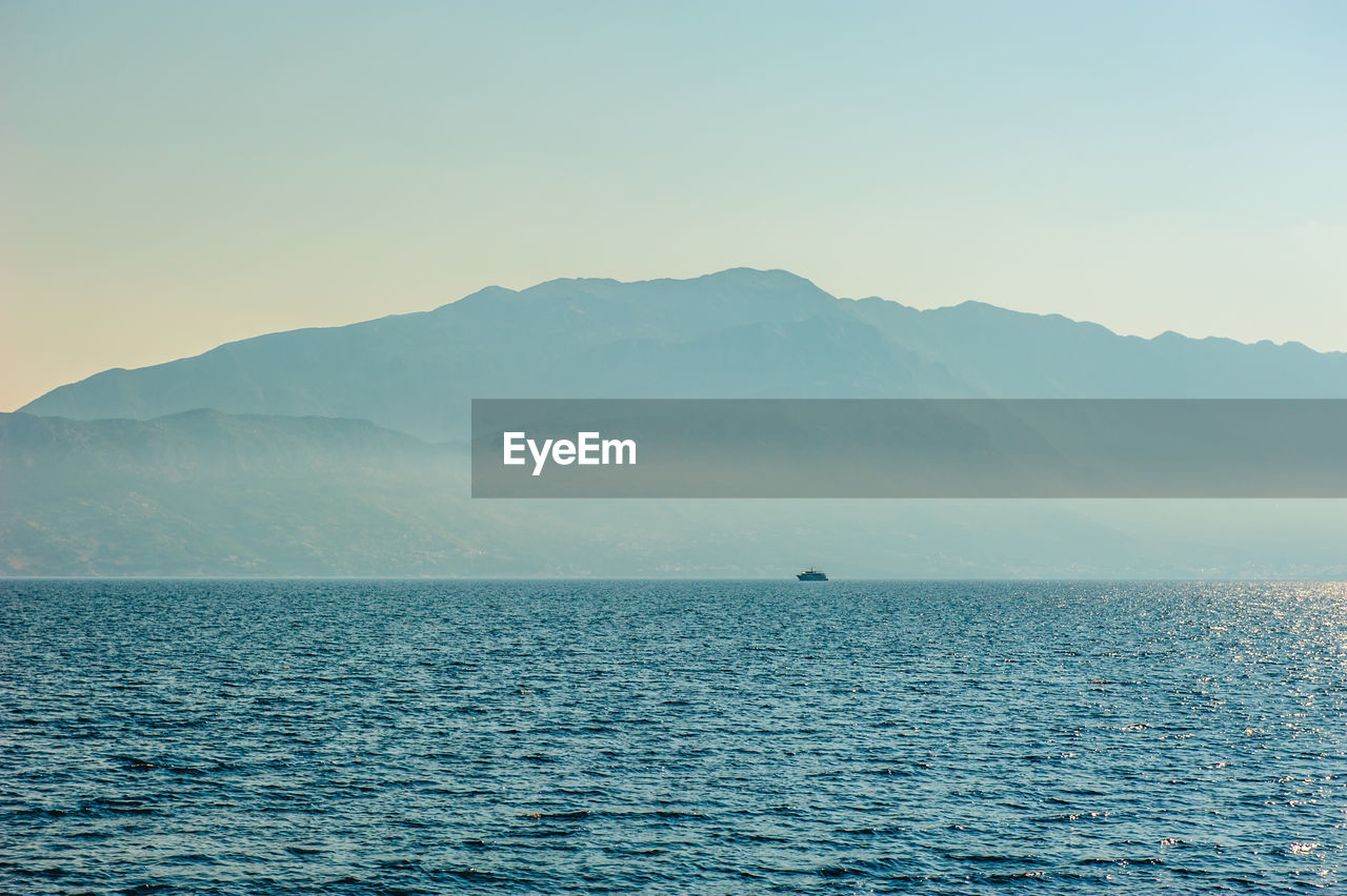 Scenic view of sea and mountains against clear sky