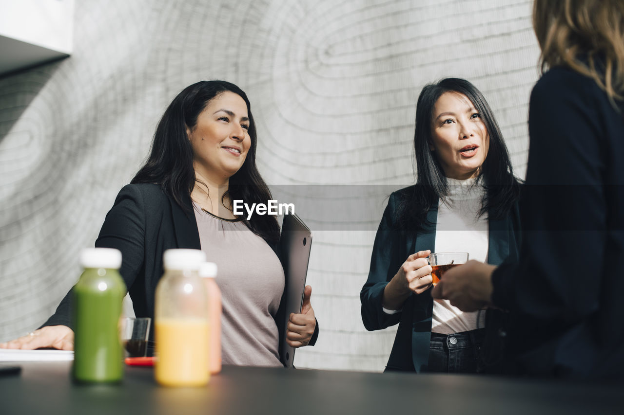 Multi-ethnic business professionals discussing while having drinks at conference event