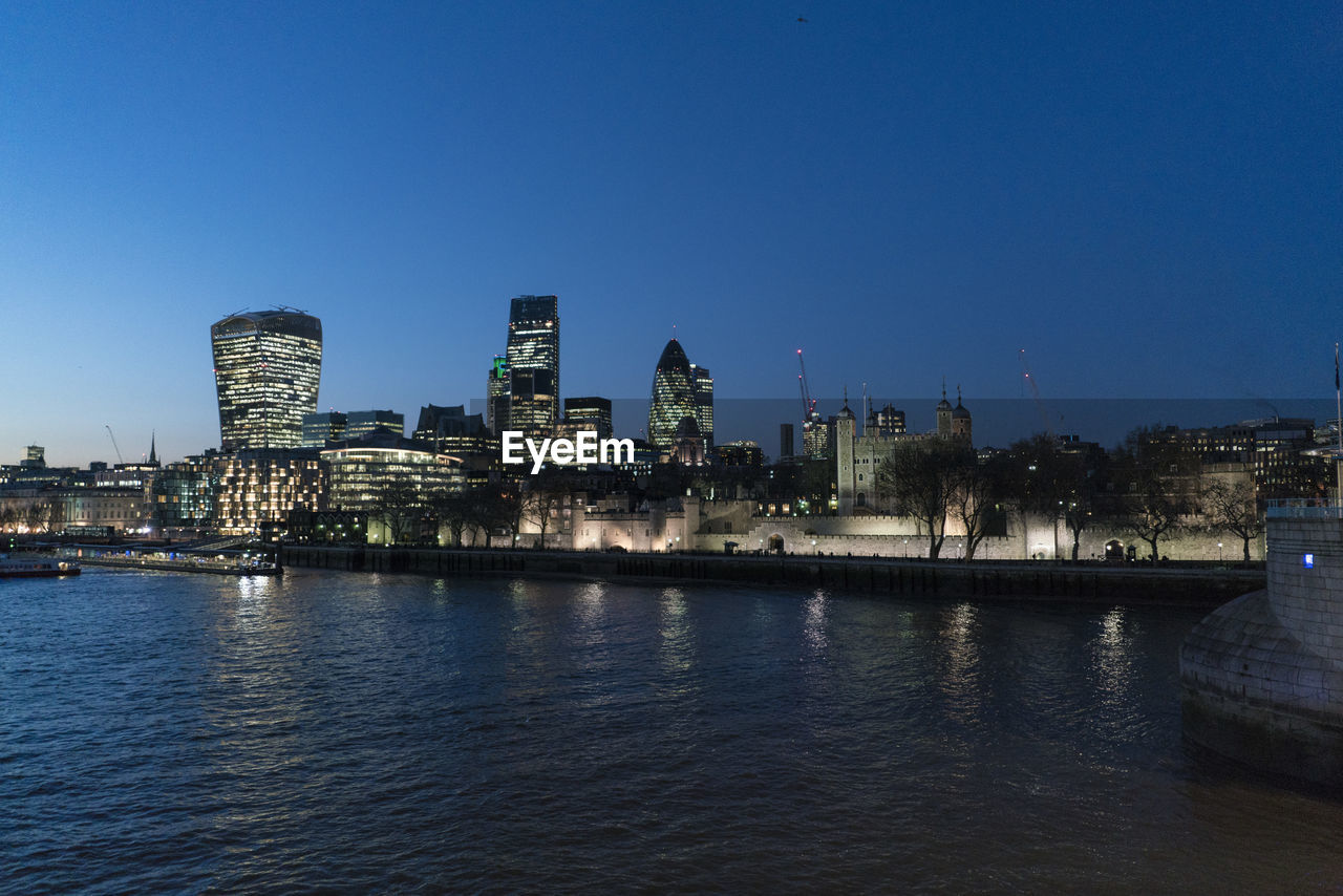 RIVER AND ILLUMINATED BUILDINGS AGAINST CLEAR BLUE SKY