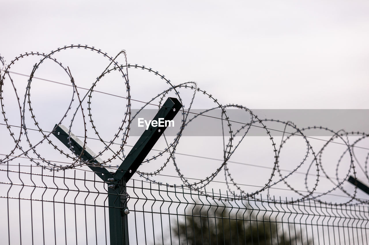 low angle view of metallic fence against sky