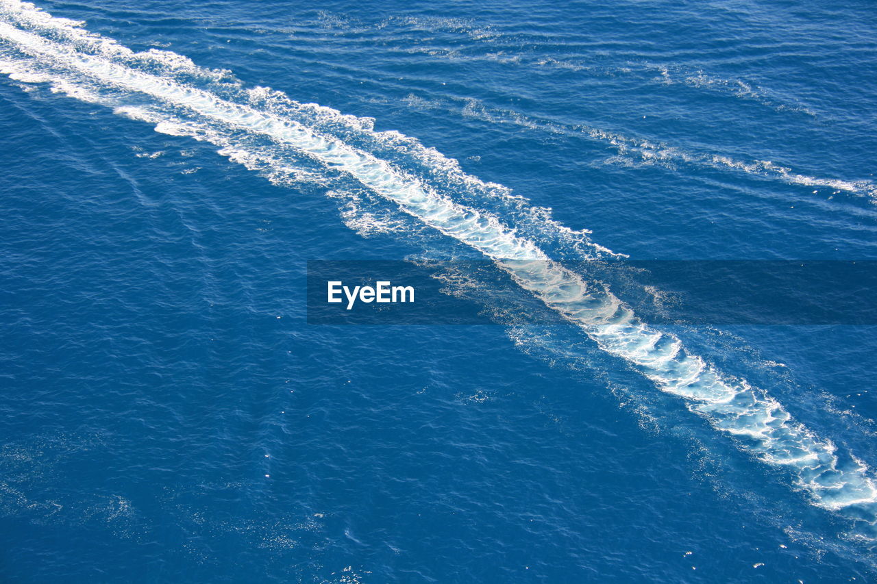 HIGH ANGLE VIEW OF WAVES BREAKING ON SEA