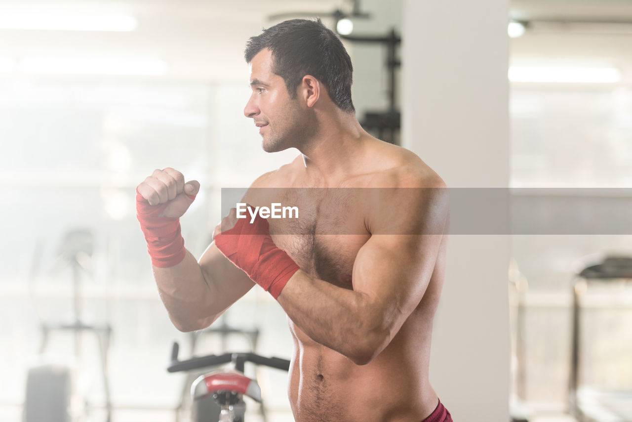 Muscular shirtless man standing in gym