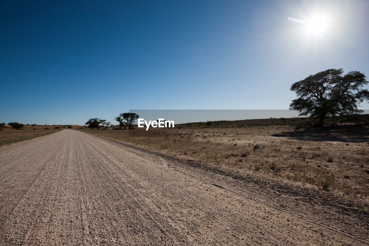 Road amidst field against clear sky