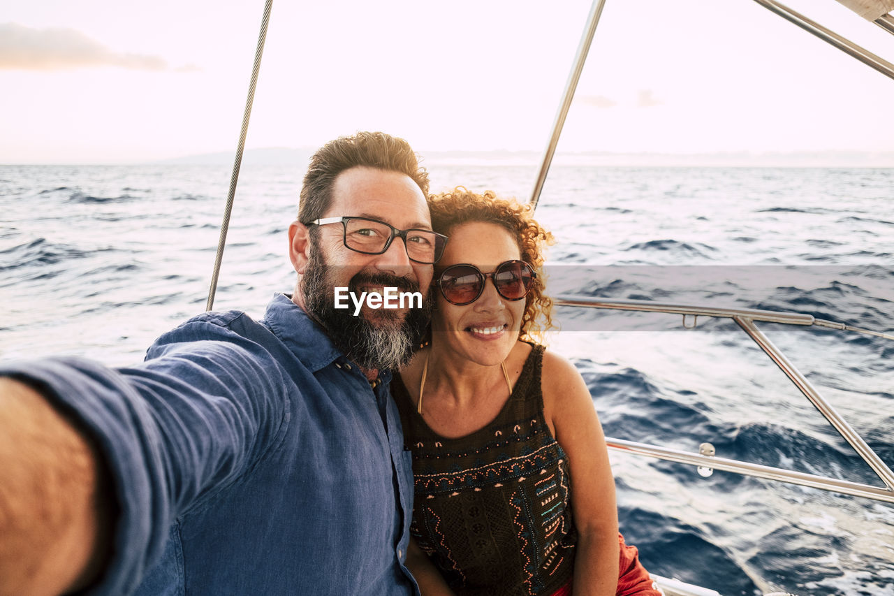 Portrait of smiling couple doing selfie at boat in sea