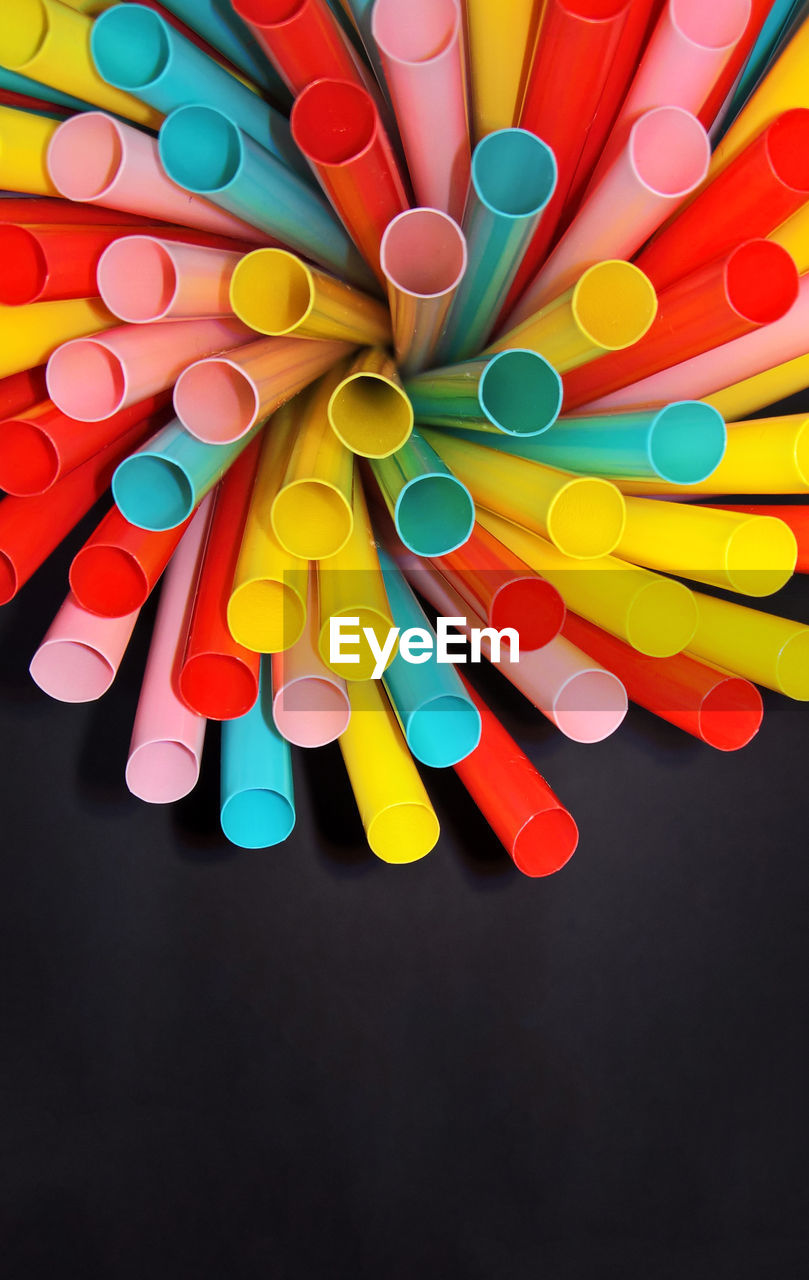 High angle view of multi colored straws on a black background 