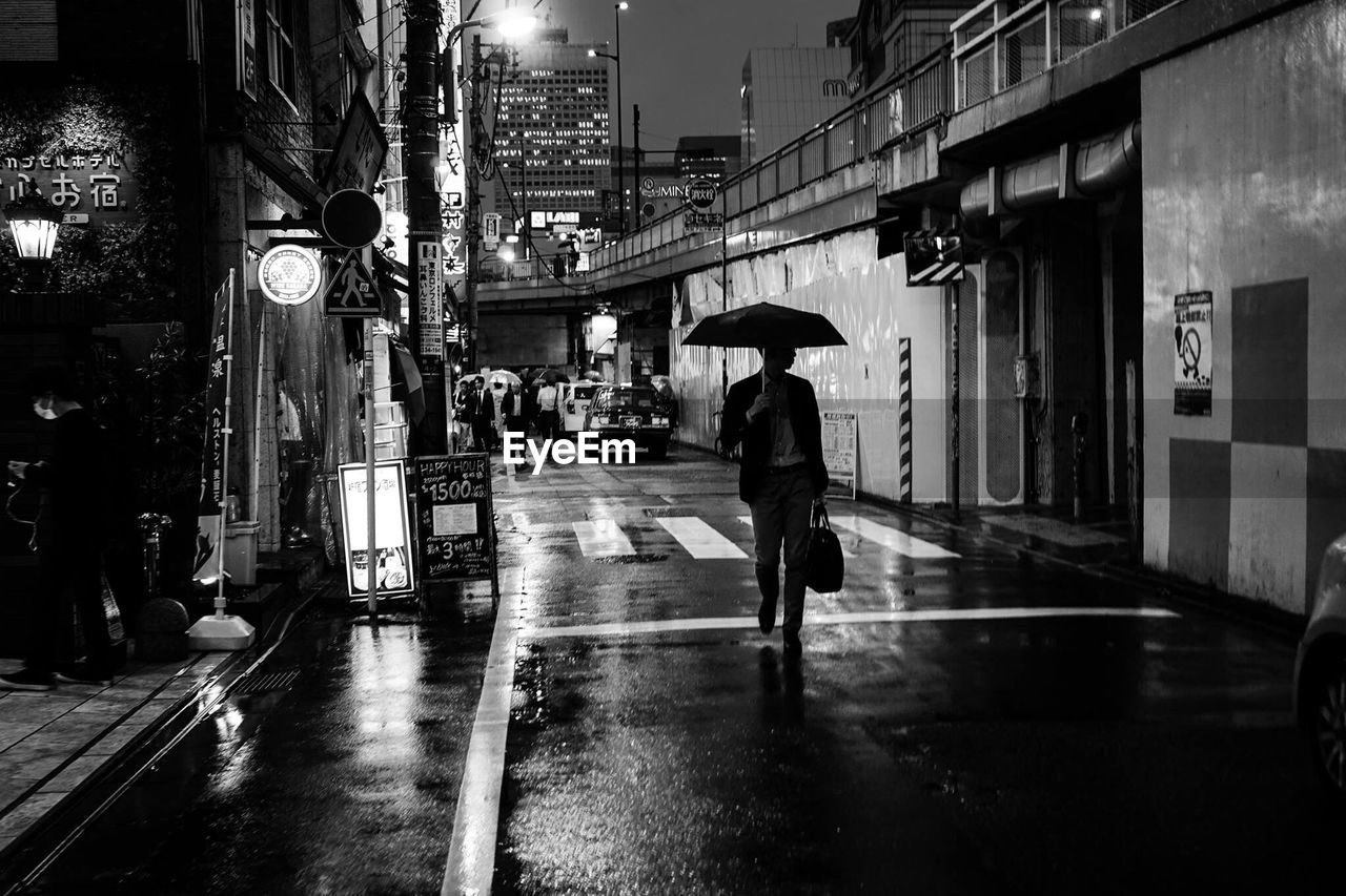 Men holding umbrella walking on road