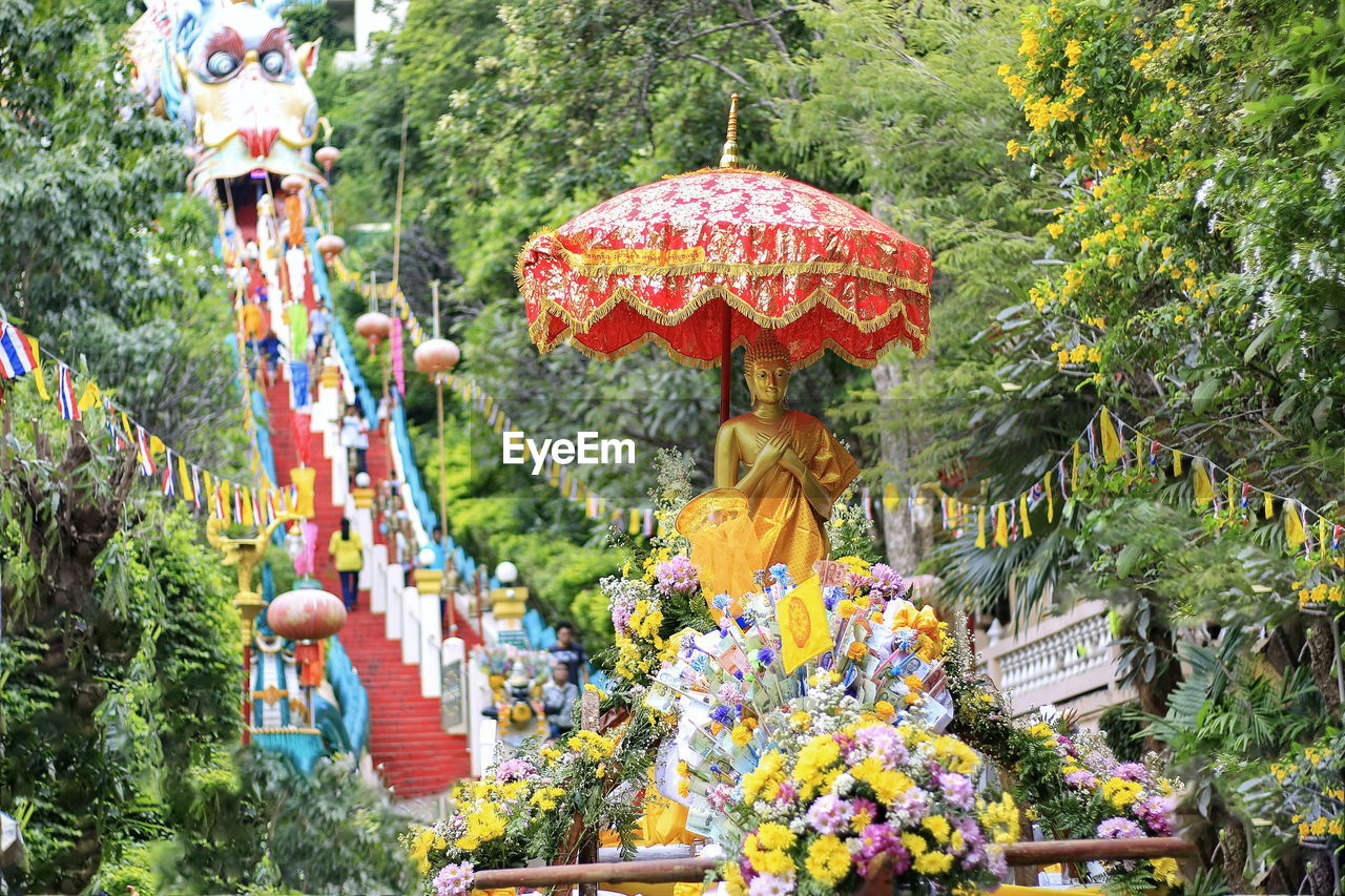 Statue of flowering plants against trees