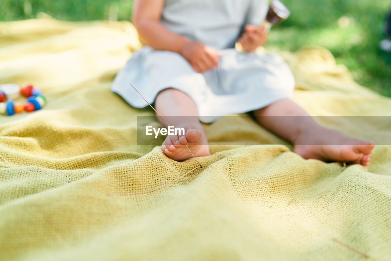 Low section of baby relaxing on bed at home