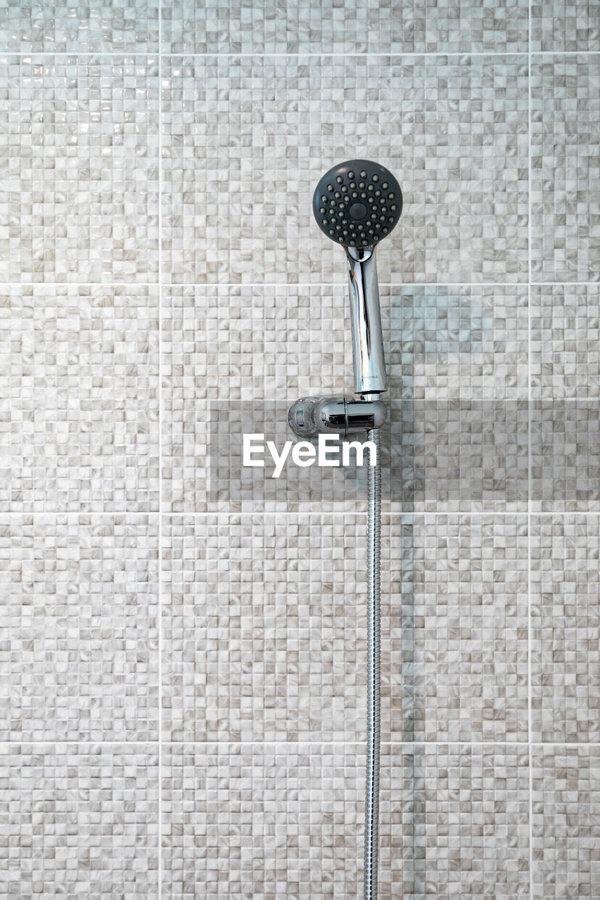 shower, plumbing fixture, no people, wall - building feature, metal, flooring, day, pattern, close-up, built structure, wall, floor, textured, lighting, architecture