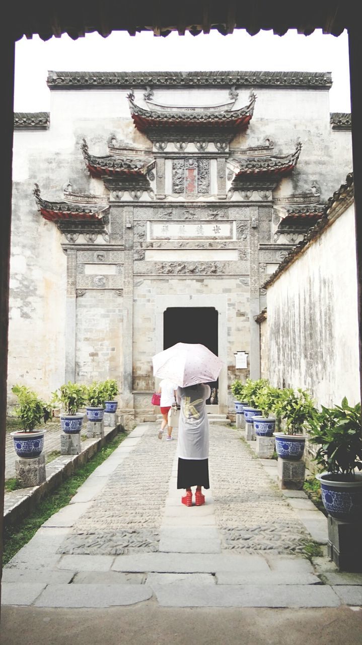 Rear view of woman standing against historic building