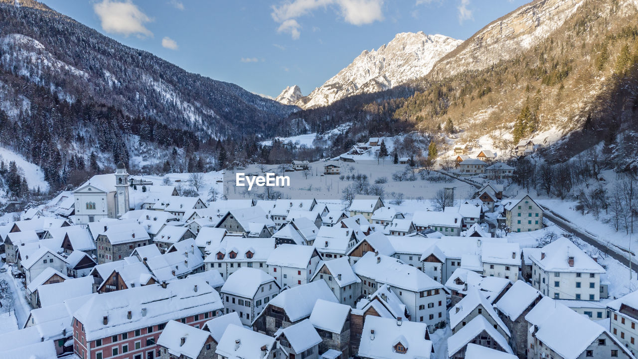 Panoramic view of buildings and snowcapped mountains against sky