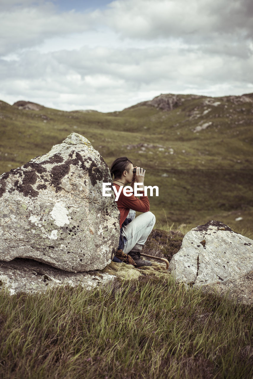 Girl leans on rock with binoculars