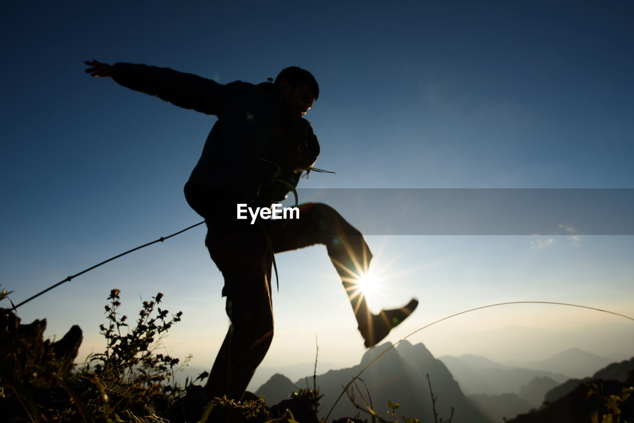 LOW ANGLE VIEW OF SILHOUETTE MAN PLAYING AGAINST CLEAR SKY