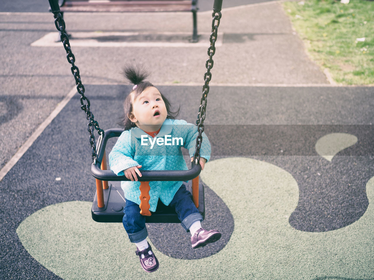 High angle view of baby girl swinging at playground