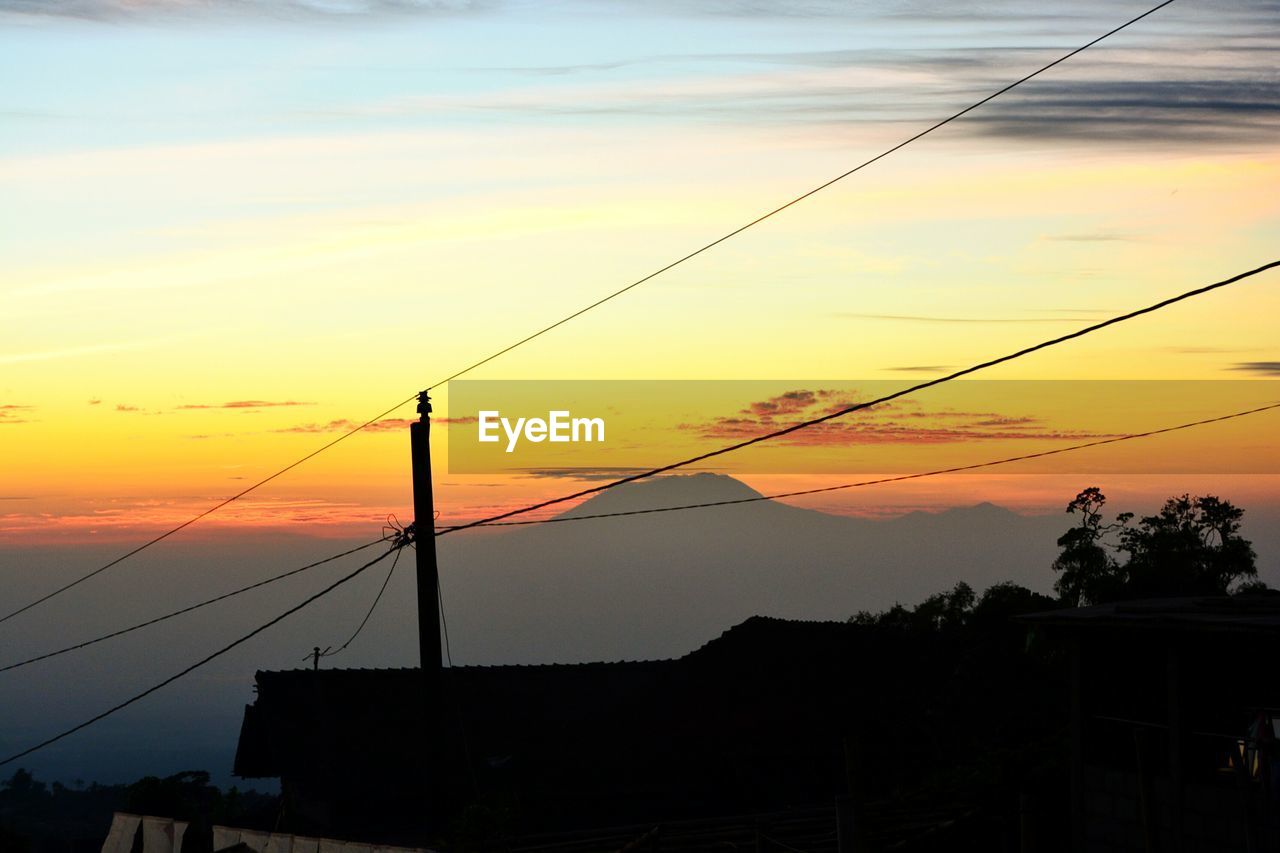 SILHOUETTE ELECTRICITY PYLONS AGAINST ORANGE SKY